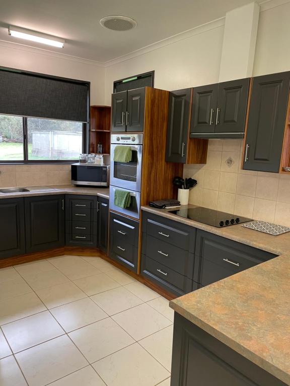 a kitchen with black cabinets and a stove top oven at Heartland Hideaway in Vivonne Bay