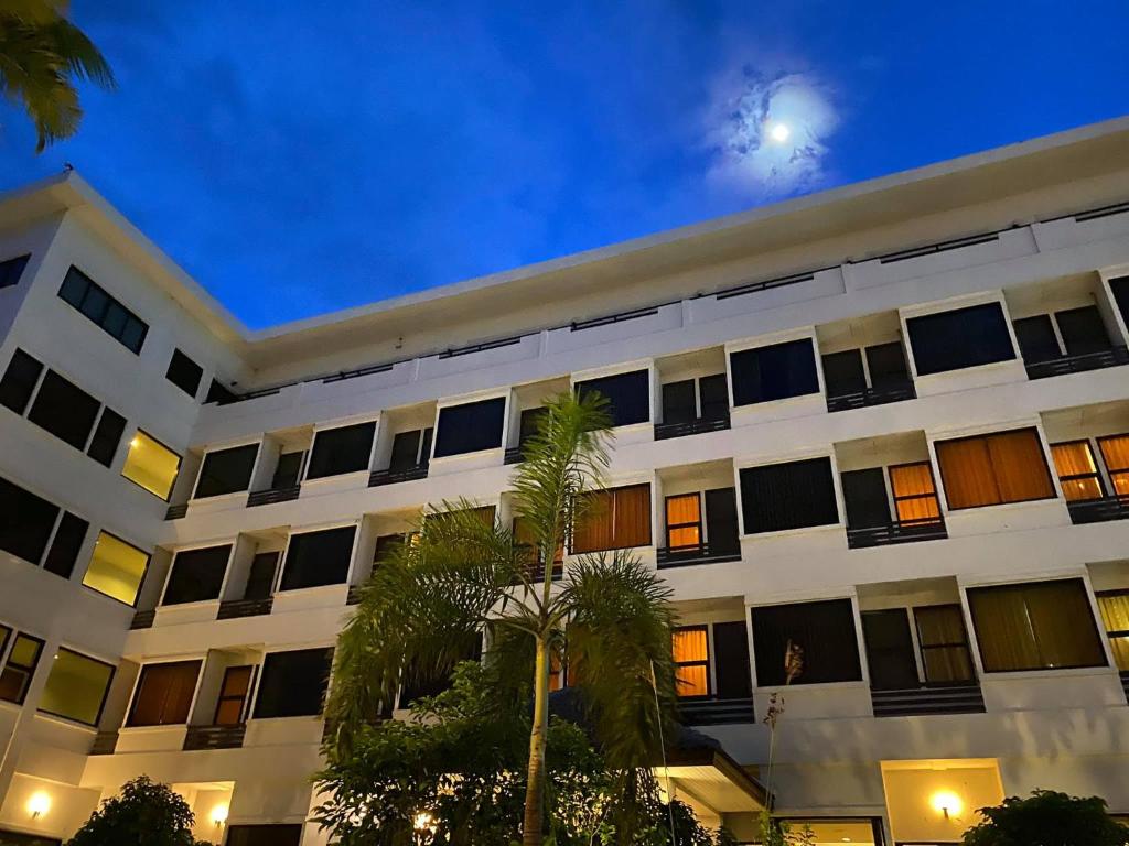 ein weißes Gebäude mit Palmen davor in der Unterkunft Naraigrand Hotel (โรงแรมนารายณ์แกรนด์) in Chai Badan