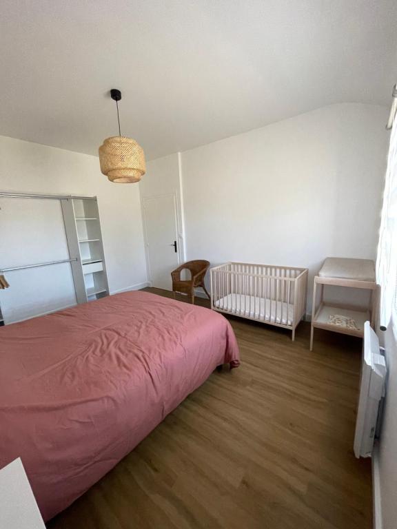 a bedroom with a pink bed and a crib at La Baronnière de Loctudy in Loctudy