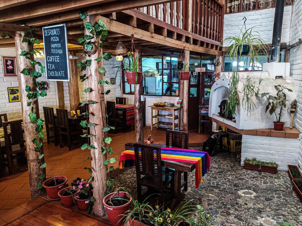 un restaurante con mesa, sillas y plantas en Chuza Longa Home en Guamote
