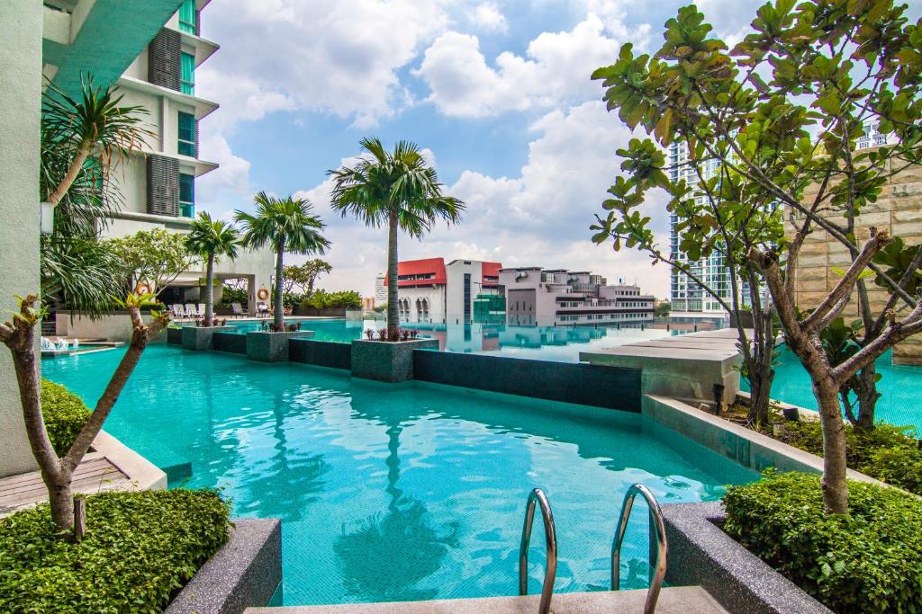a swimming pool at a resort with palm trees and buildings at Swiss Suites by Plush in Kuala Lumpur