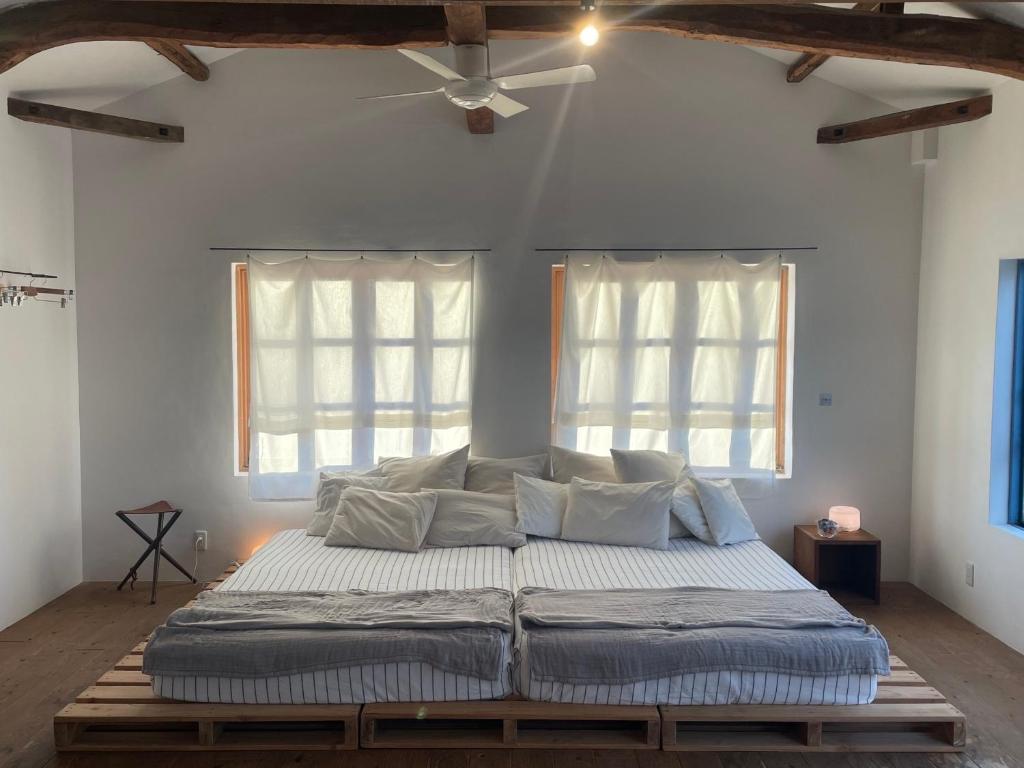 duże łóżko w pokoju z 2 oknami w obiekcie Jasmine w mieście Hukue