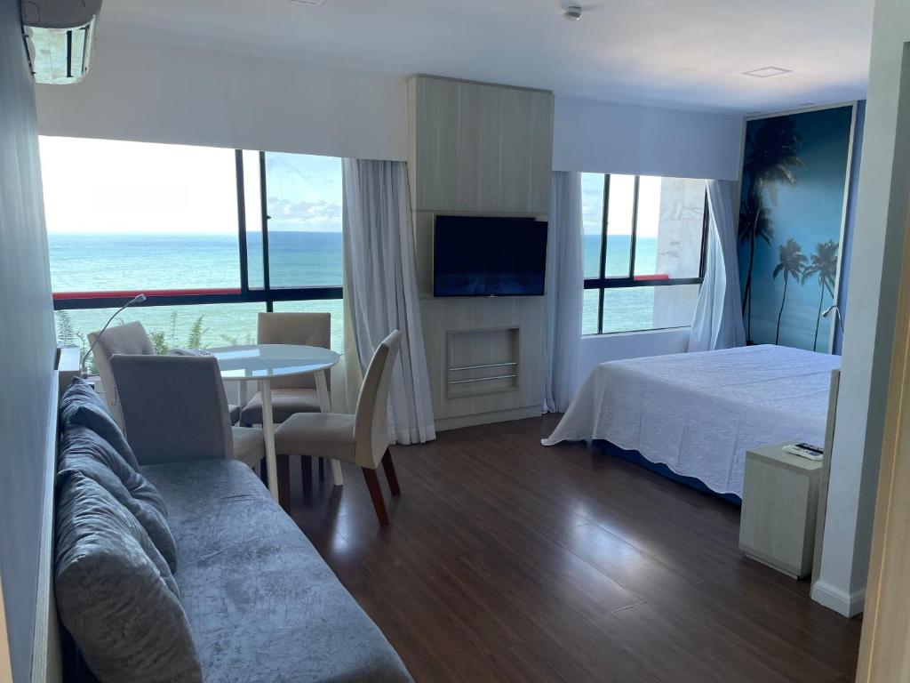 - une chambre avec un lit et une table offrant une vue sur l'océan dans l'établissement Flat Recife - Boa Viagem, à Récife