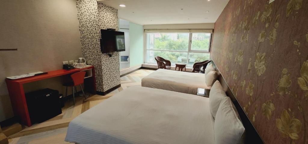 a hotel room with two beds and a television at Ximen Garden Inn in Taipei