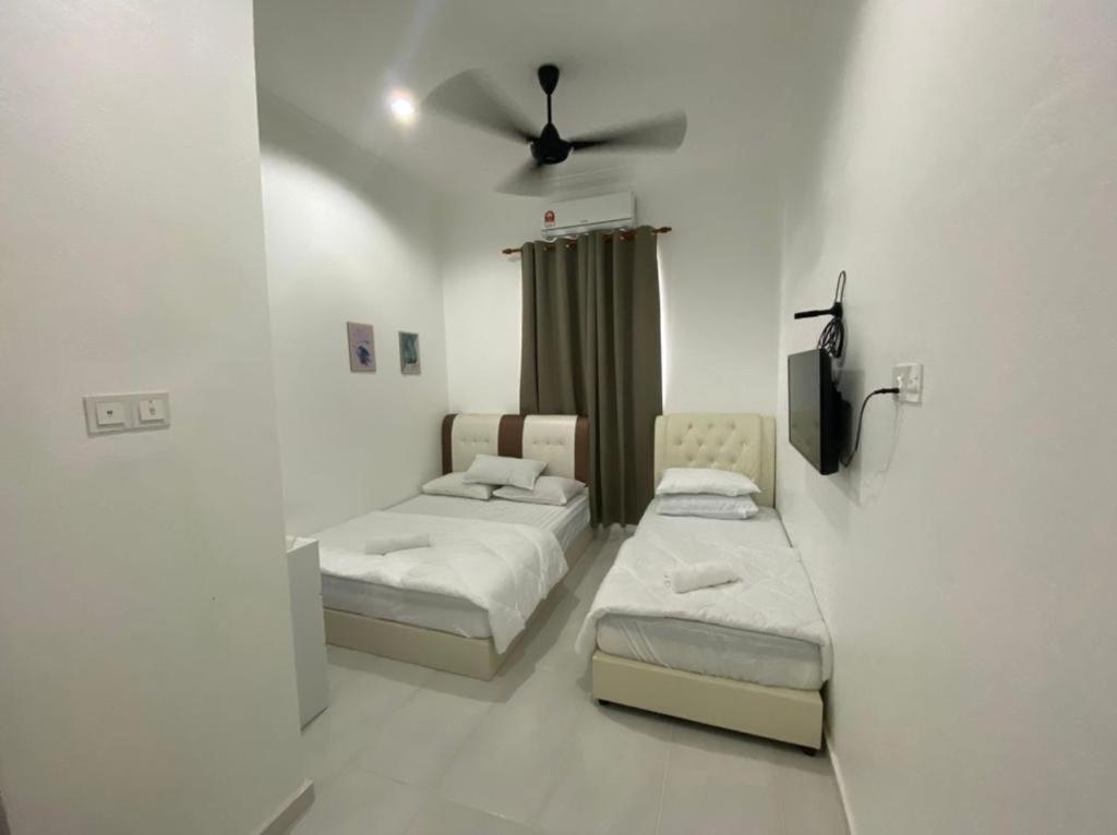 a room with two beds and a ceiling fan at dsinggahPCB Guest House in Kota Bharu
