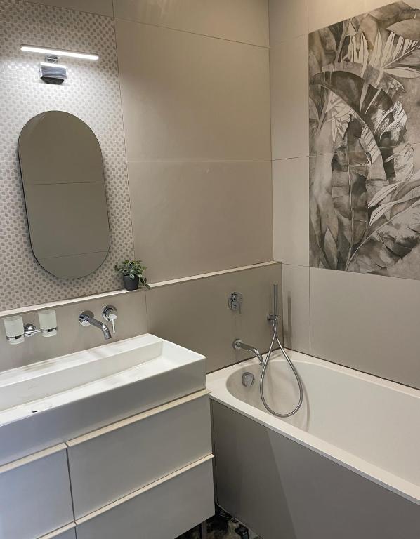 W łazience znajduje się umywalka, wanna i lustro. w obiekcie Appartement Le Palais du Commerce w mieście Vichy