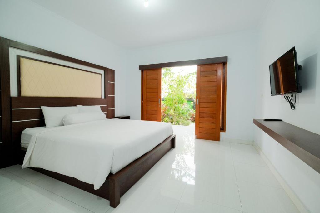 Kadek Bagus Guesthouse Denpasar Mitra RedDoorz في كيروبوكان: غرفة نوم بسرير وتلفزيون بشاشة مسطحة