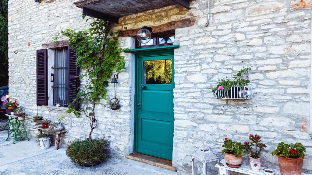 a green door on a stone house with potted plants at A Casa di Anna in Cortemilia