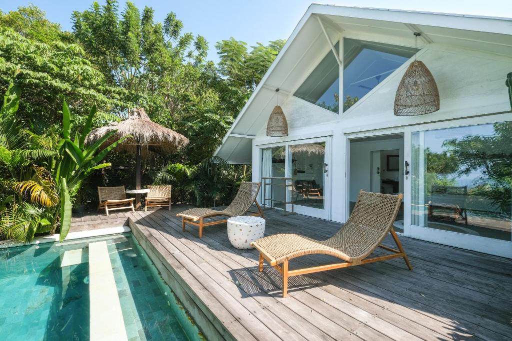 a house with a swimming pool and chairs on a deck at Salty Breeze Bali in Ungasan
