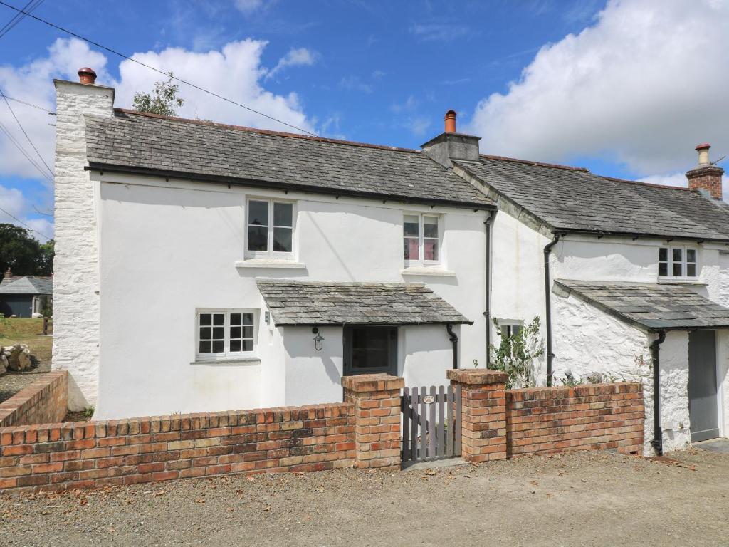 a white house with a brick fence in front of it at Trelash Cottage in Launceston