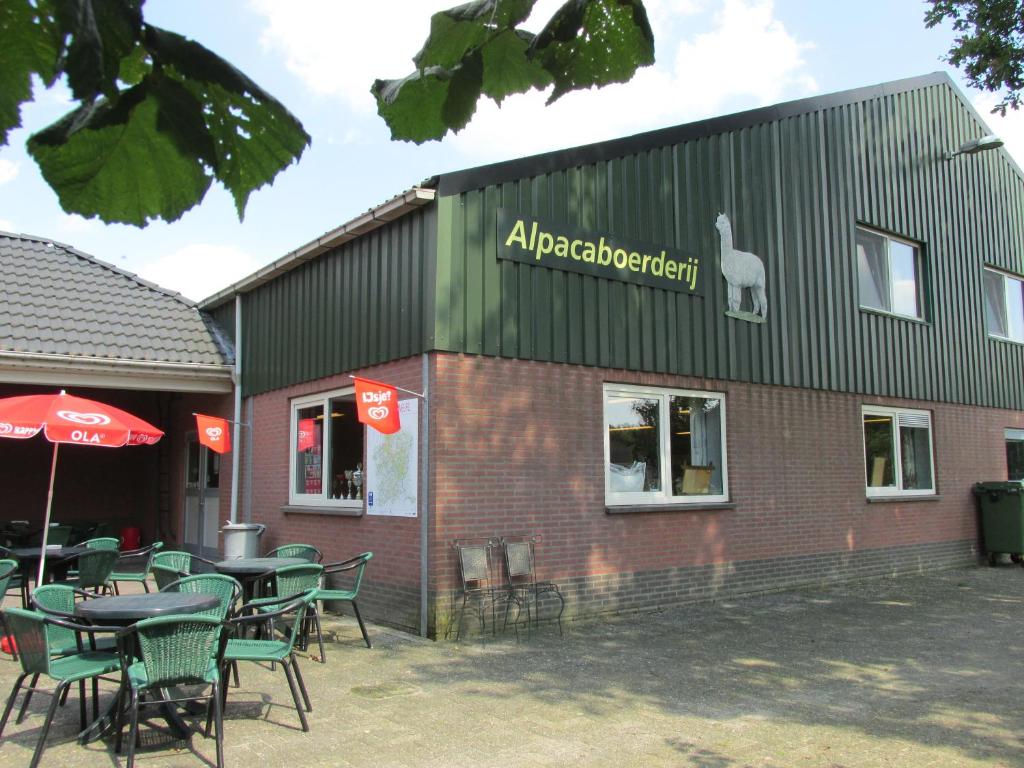 een restaurant met tafels en stoelen voor een gebouw bij De Alpacaboerderij in Bocholt