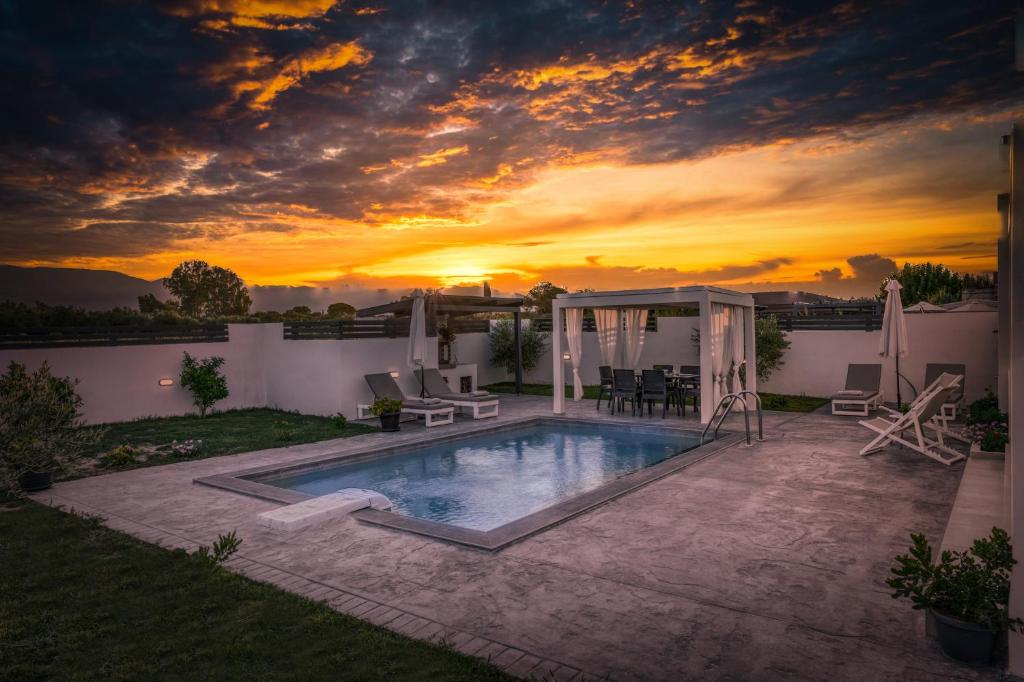 una piscina con puesta de sol en el fondo en Blue Wind Villa II en Sarakinádhon