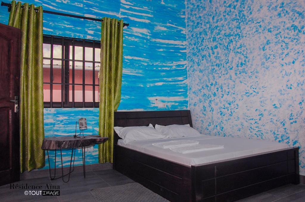 Schlafzimmer mit einem Bett mit Wandgemälde in der Unterkunft RESIDENCE AINA in Abomey-Calavi