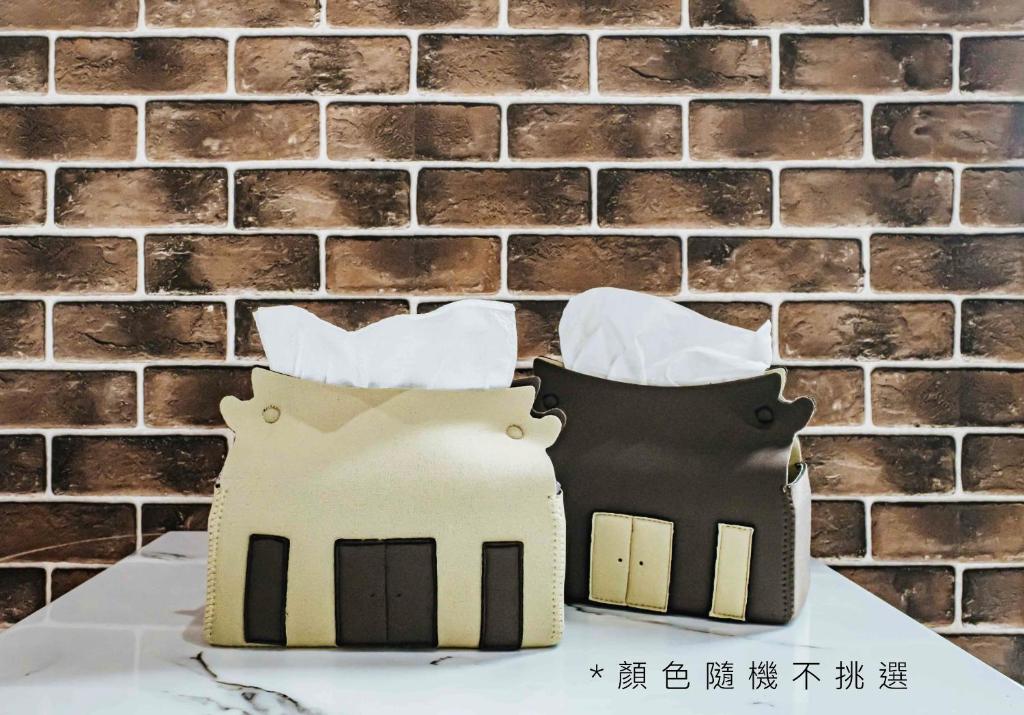 two cut out houses on a table in front of a brick wall at Jia Hsin Garden Hotel in Tainan