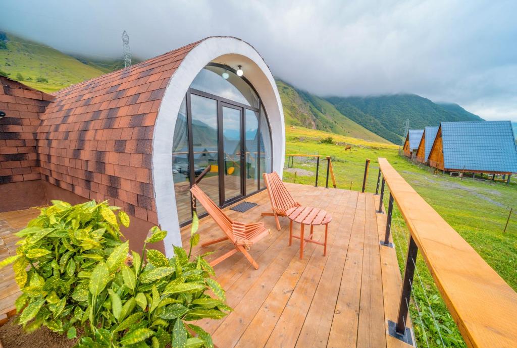 卡茲別吉的住宿－Kazbegi Glamping，一个带两把椅子的木制甲板和一座建筑