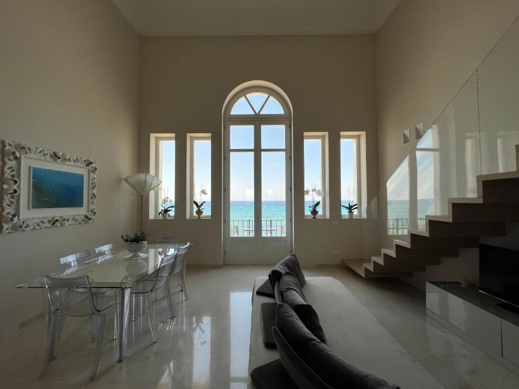 a living room with a table and chairs and the ocean at Luxury Loft on the Sea in Trapani