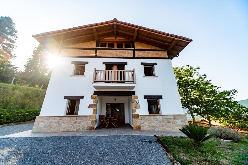 a large white house with a balcony on top at LAGA SURF Villa in Ibarrangelu