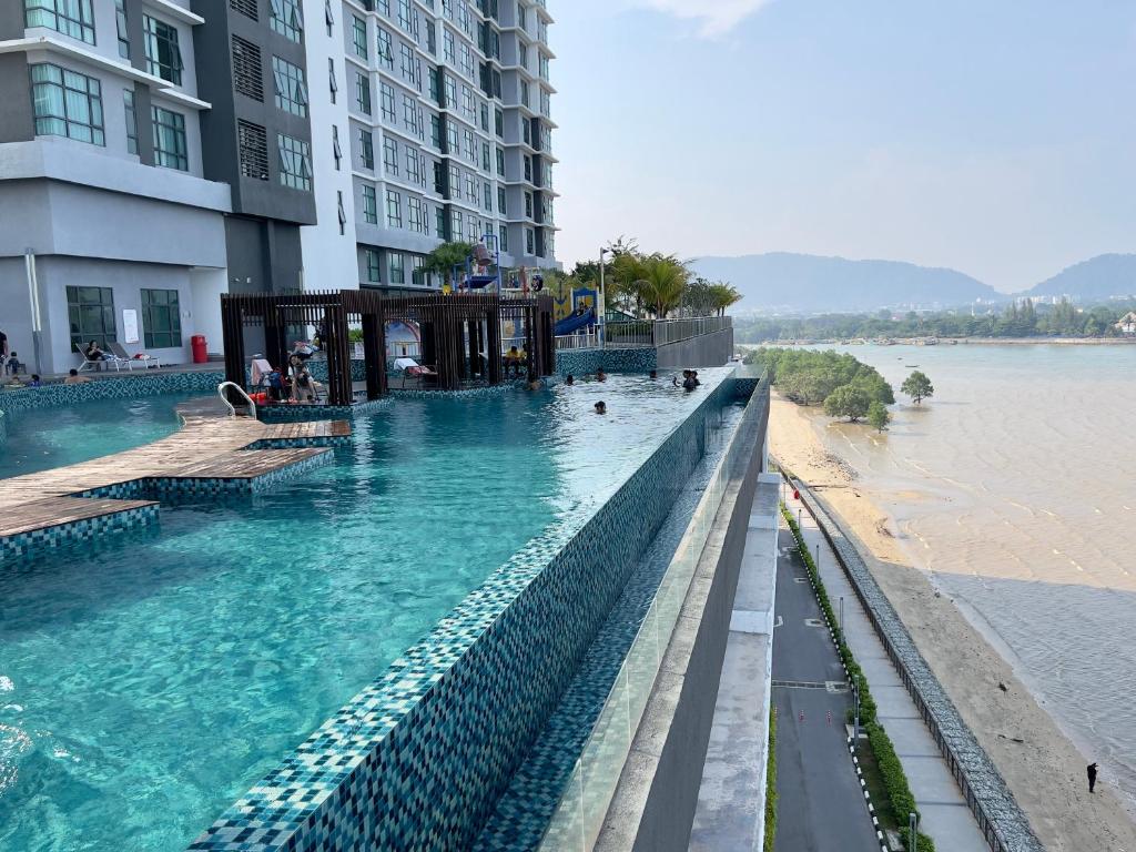 a swimming pool next to a building and a body of water at IMPERIUM RESIDENCE KUANTAN [Seaview] Family Suite in Kuantan
