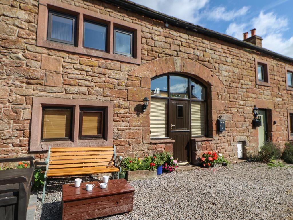 a brick building with a bench in front of it at 1 Yew Tree Cottages in Penrith