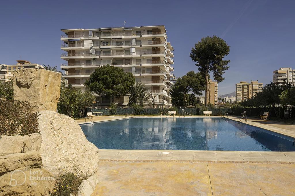 a large swimming pool in front of a tall building at San Juan Live in Alicante