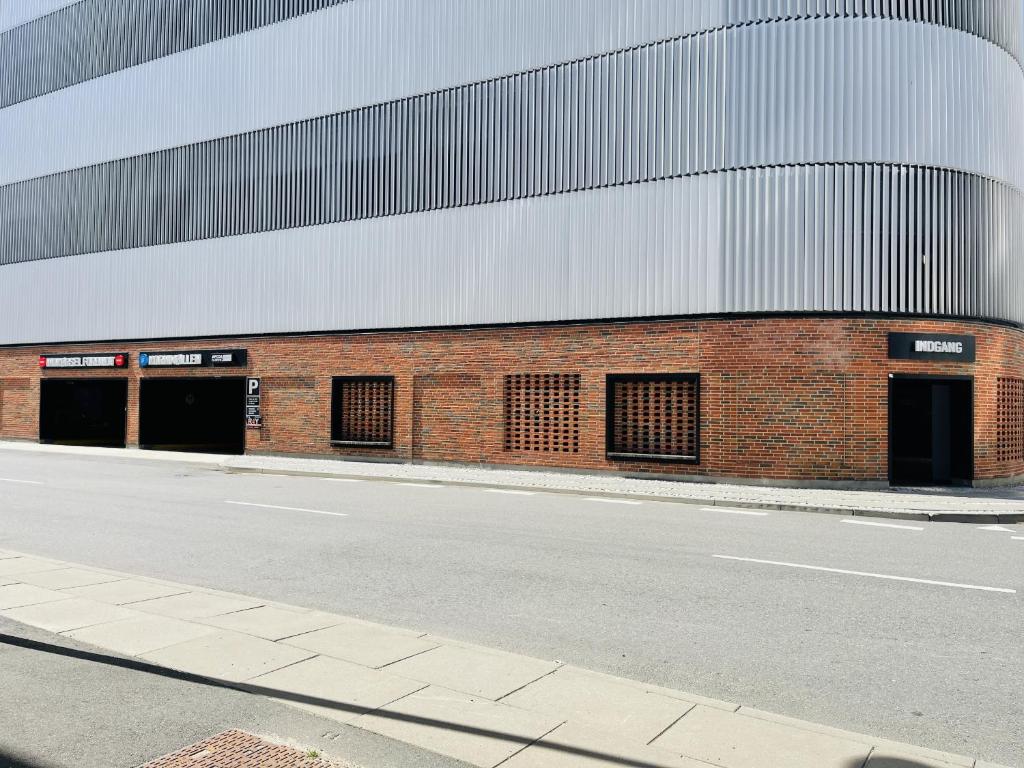 a red brick building with three doors on a street at aday - Harbor Groundfloor Own Entrance - Studio in Aalborg