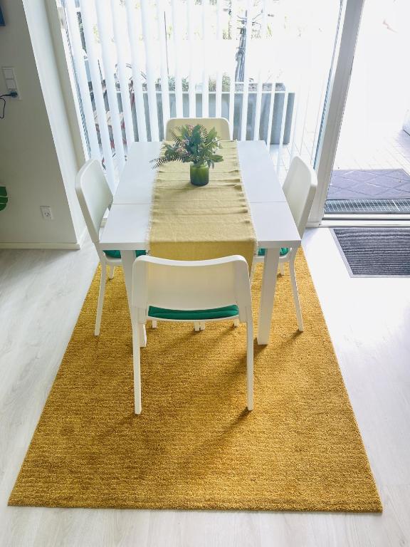 a white dining table with white chairs and a rug at aday - Harbor Groundfloor Own Entrance - Studio in Aalborg