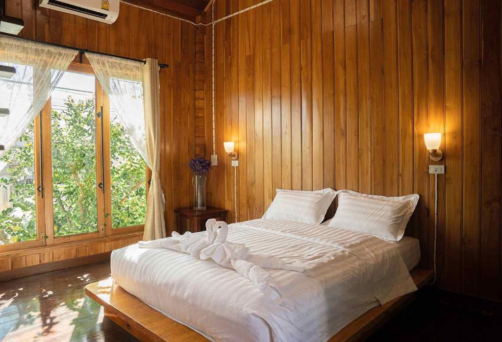 um quarto com uma grande cama branca e paredes de madeira em Srisanor Boutique Hotel em Prachuap Khiri Khan