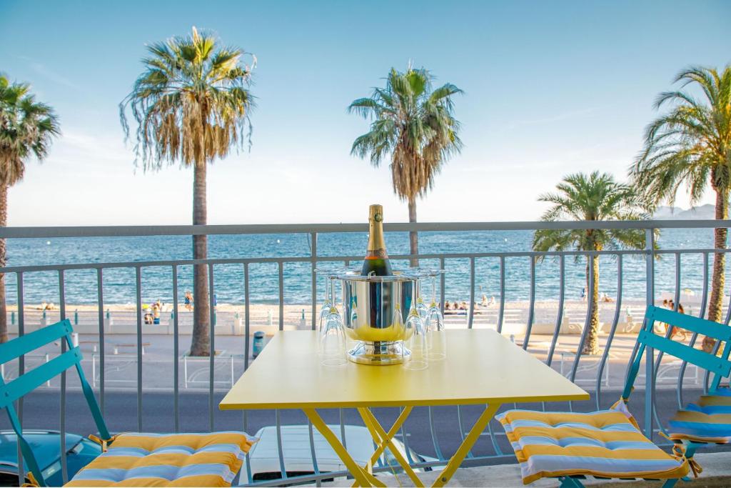 a table with a bottle of wine on a balcony overlooking the beach at Bel Appartement Face à La Mer Près Du Centre - Le Voilier in Cannes