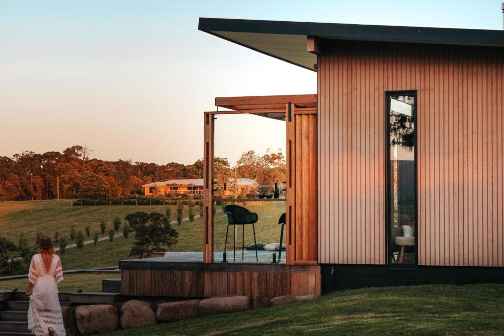 a woman standing outside of a house with a view of a field at Tawillah Milton Luxury Retreat in Milton