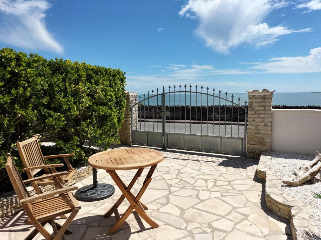 d'une terrasse avec une table, des chaises et une clôture. dans l'établissement Venez vous ressourcer sur les falaises de Meschers, à Meschers-sur-Gironde