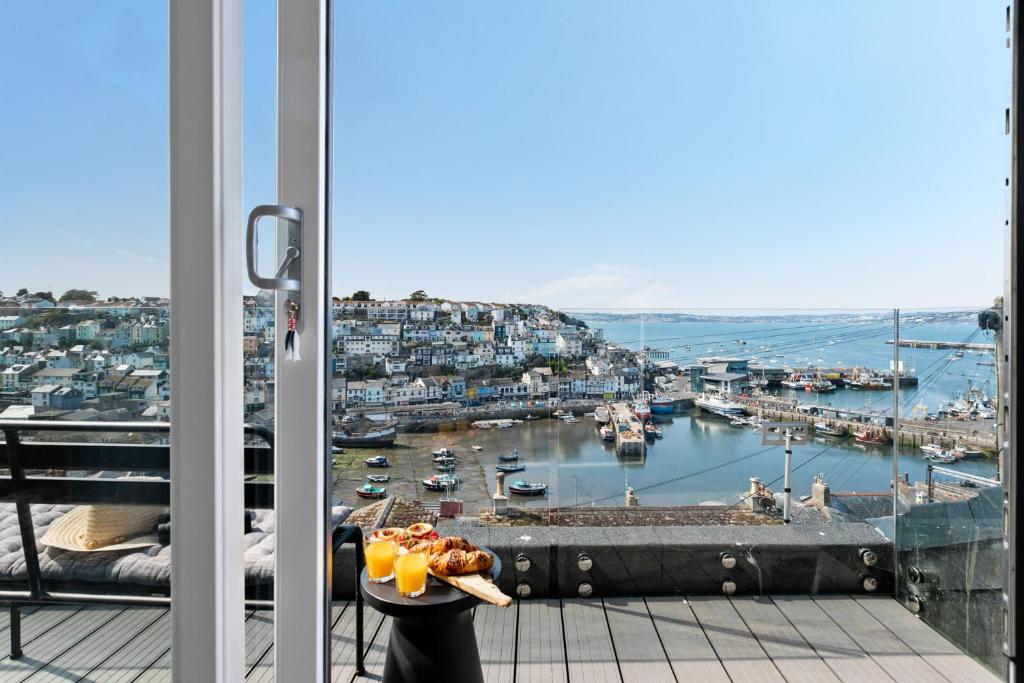a view of a harbor from a balcony with a table with drinks at The Captain's Cottage, Brixham in Brixham