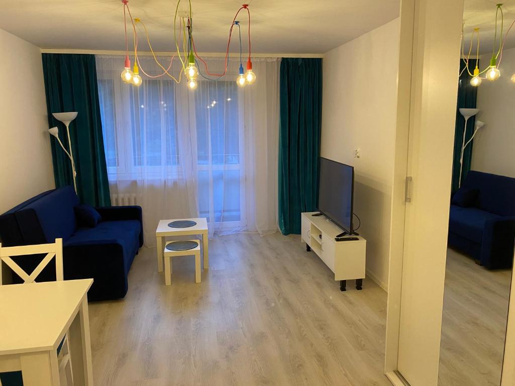 ein Wohnzimmer mit einem blauen Sofa und einem TV in der Unterkunft Turkusowy Zakątek Głogów in Głogów