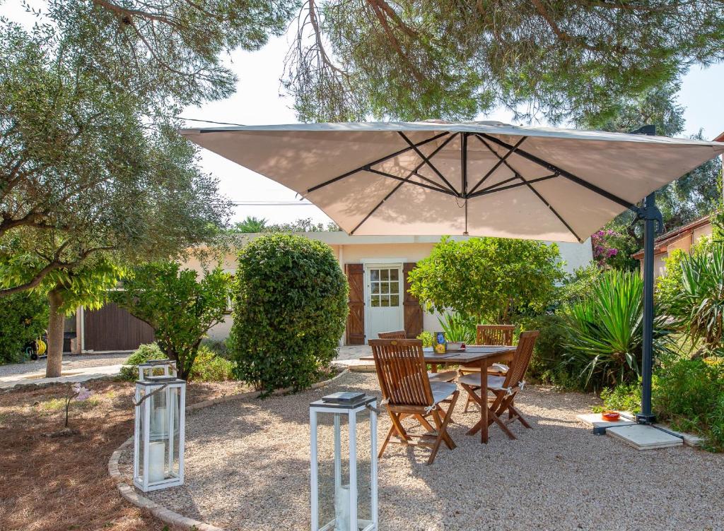 une table et des chaises sous un grand parasol dans l'établissement Haus mit Garten über der Bucht von Cannes, à Vallauris