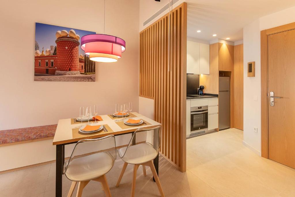 una cucina con tavolo con due sedie e luce rosa di C&C Apartments a Figueres