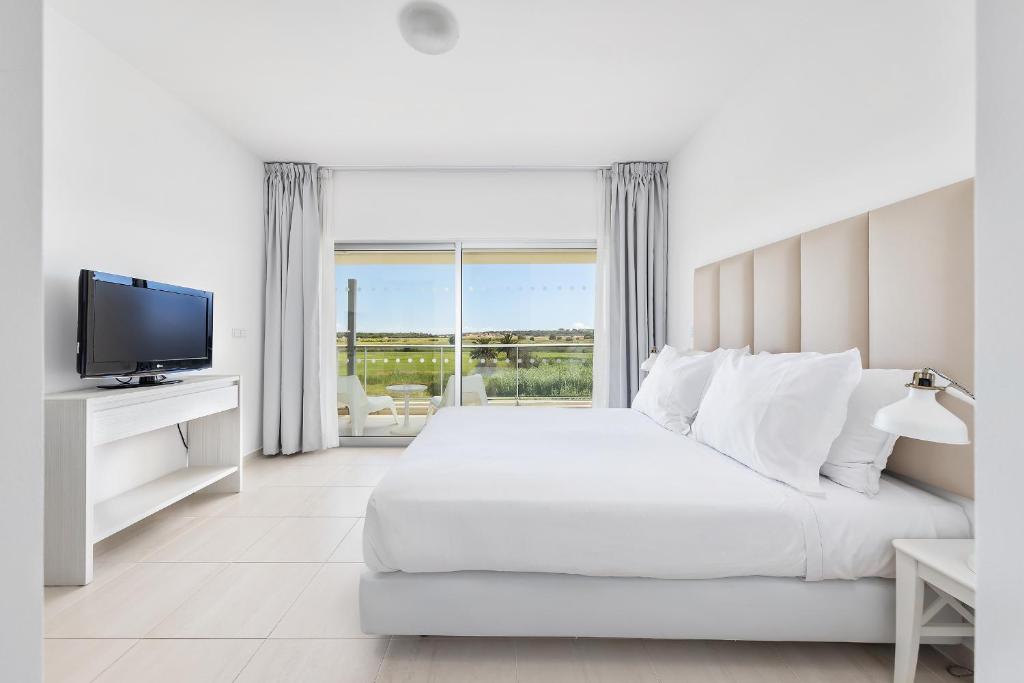 een witte slaapkamer met een groot bed en een televisie bij Laguna - Vilamoura in Vilamoura