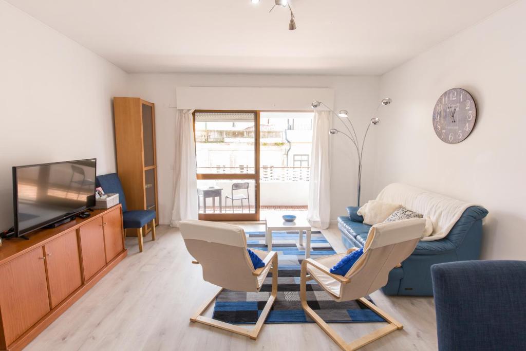 uma sala de estar com um sofá azul e duas cadeiras em Metro Lapa House with sunny balcony and A/C no Porto