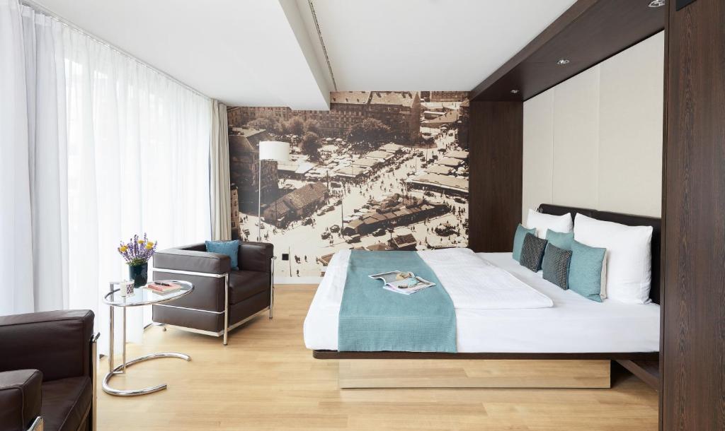 a bedroom with a bed and a couch and a chair at Living Hotel Das Viktualienmarkt in Munich