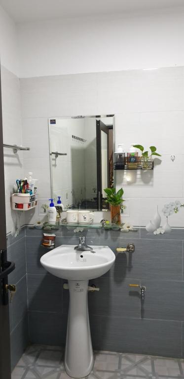 een badkamer met een witte wastafel en een spiegel bij An Homestay in Yen