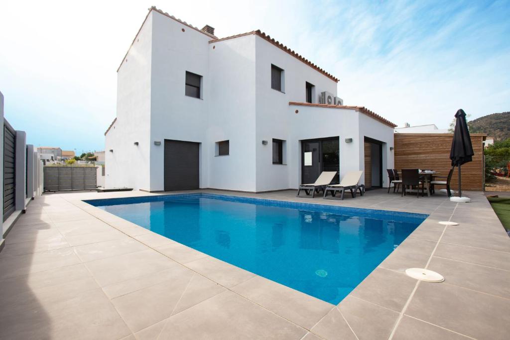 une villa avec une piscine en face d'une maison dans l'établissement Vila Mas Busca 72 - Roses Costa Brava, à Roses