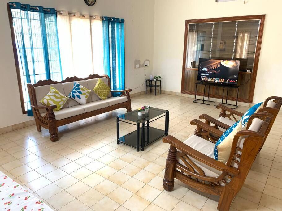 a living room with two couches and a tv at Kamala Holiday Home in Mysore