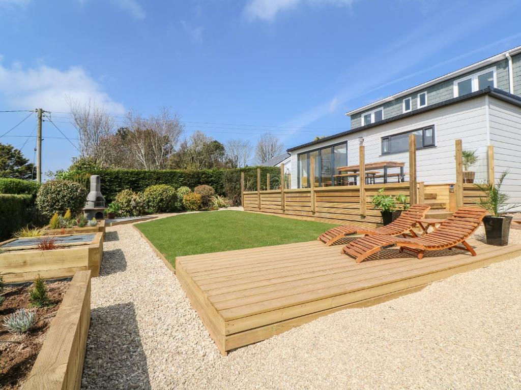 a backyard with a wooden deck with chairs and a house at Craybourne in Falmouth