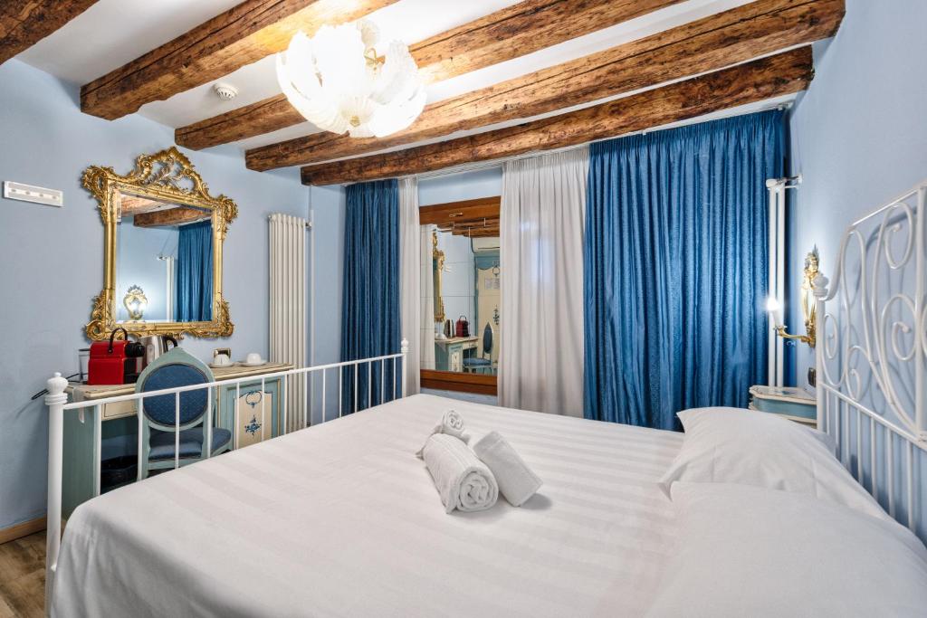 a bedroom with a white bed and blue curtains at Piccolo Vecellio in Venice