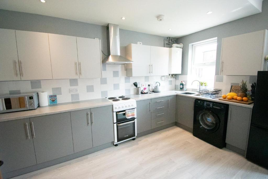 a kitchen with white cabinets and a washing machine at Ideal Lodgings in Bury in Bury