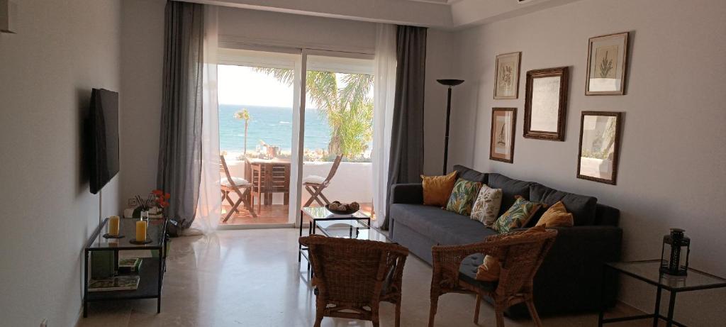 sala de estar con sofá y vistas al océano en Espectacular apartamento primera linea de playa - Golf en Estepona