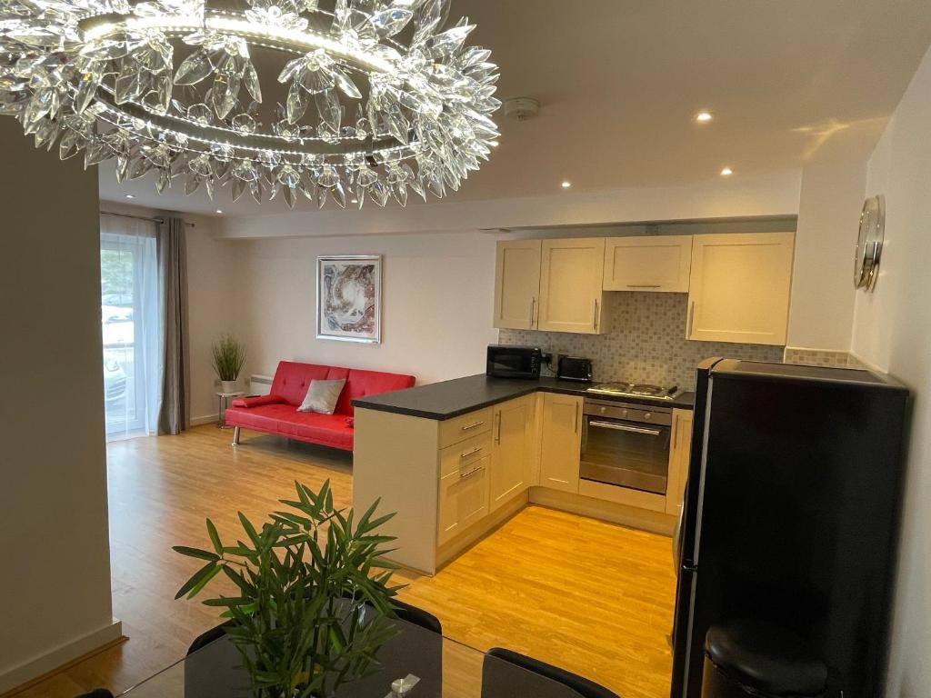 een keuken en een woonkamer met een rode bank bij Moda Wigan - Stylish 2 Bed Apartment Central Wigan in Wigan