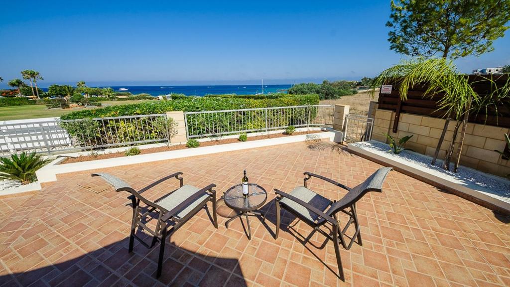 een patio met een tafel en stoelen en de oceaan bij Protaras Holiday Villa 196 in Protaras