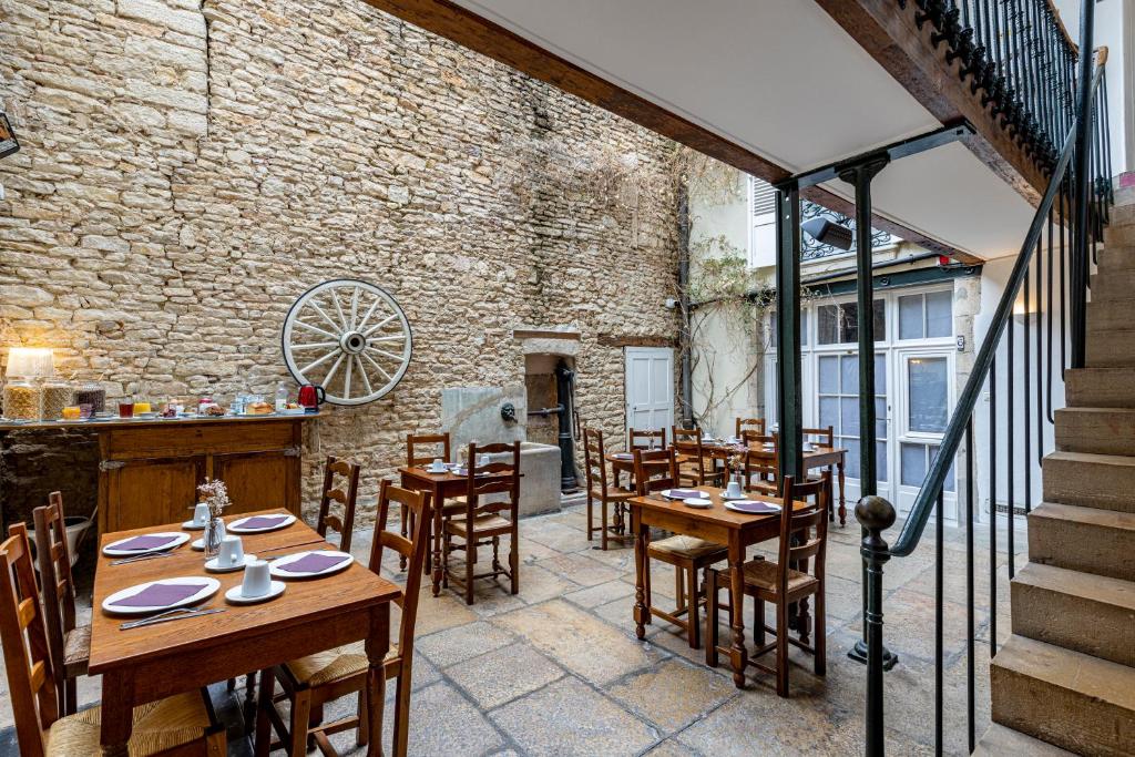 a restaurant with wooden tables and chairs and a brick wall at Hôtel des Tonneliers in Beaune
