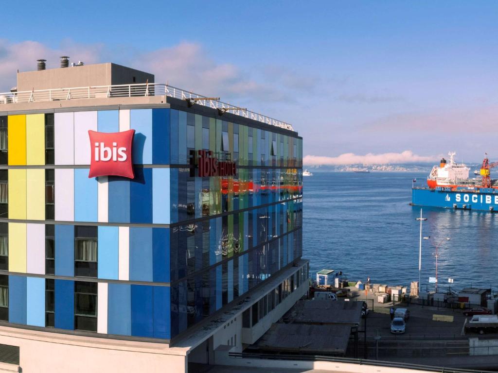 un bâtiment coloré avec un bateau de croisière dans l'eau dans l'établissement ibis Valparaiso, à Valparaíso