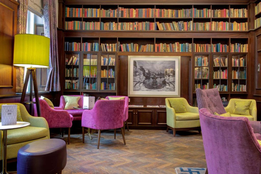 ロンドンにあるベスト ウェスタン モーニントン ホテル ハイド パークの紫色の椅子と本棚がある図書室