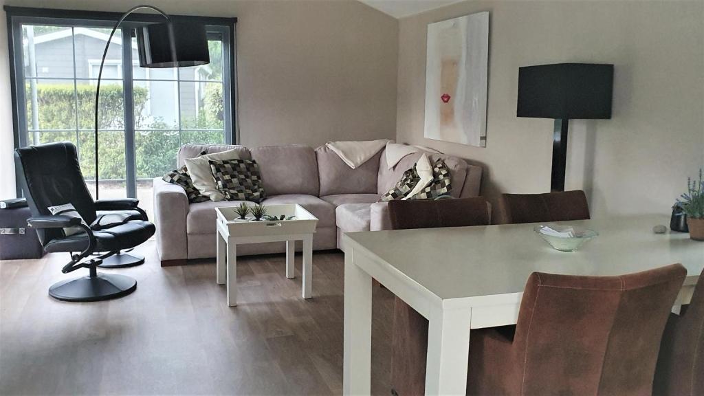 ein Wohnzimmer mit einem Sofa und einem Tisch in der Unterkunft Mooi Chalet voor een Top Vakantie aan Zee in Biggekerke